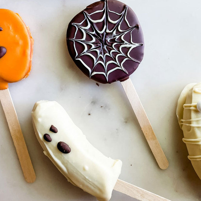 Photo of festive Halloween Fruit Pops decorated with chocolate and colorant to look like pumpkins, ghosts and mummies.