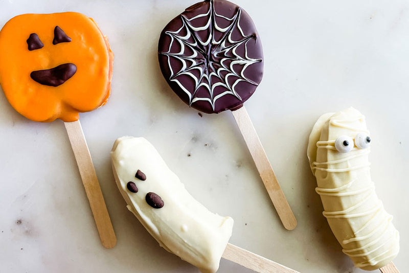 Photo of festive Halloween Fruit Pops decorated with chocolate and colorant to look like pumpkins, ghosts and mummies.