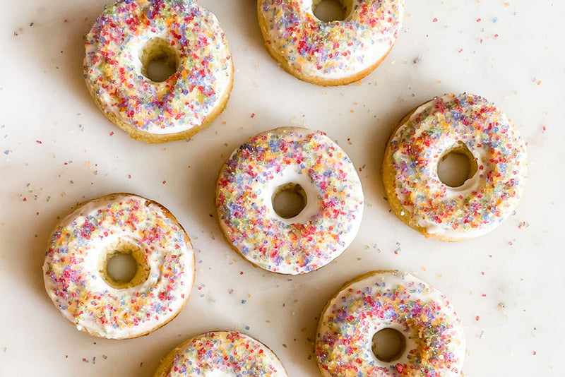 Photo of Paleo Vanilla Donuts with icing and Rainbow Crystal Sugar sprinkles