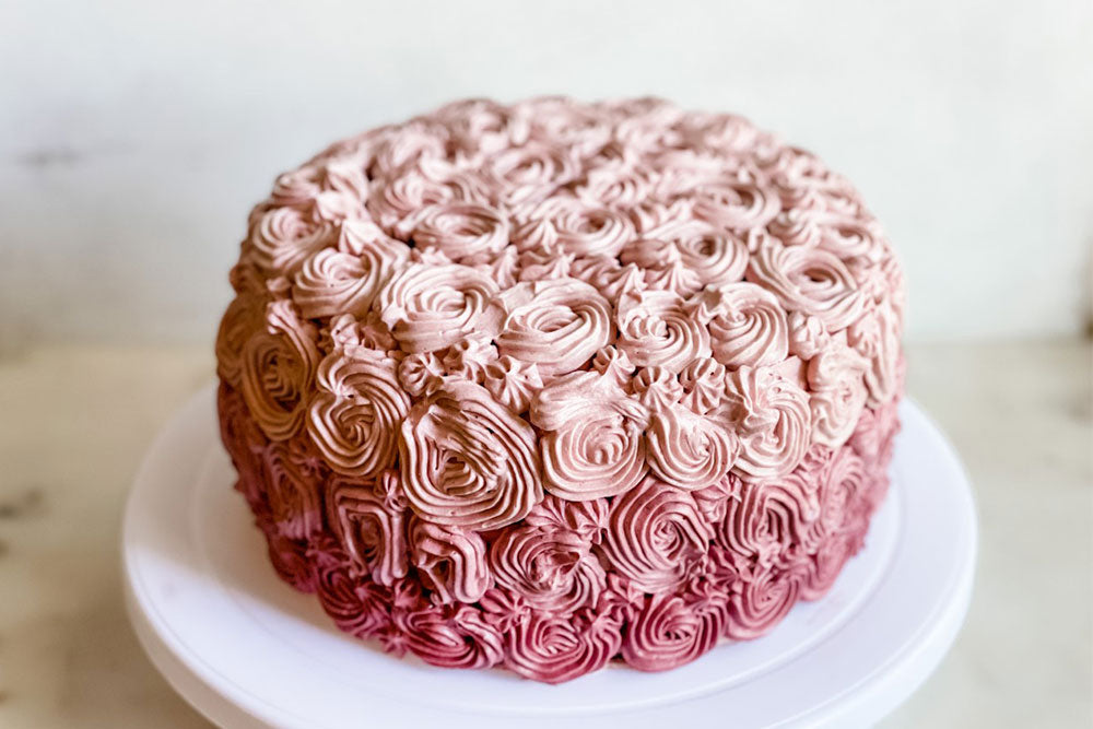 Photo of a pink ombre cake with swirls of buttercream frosting