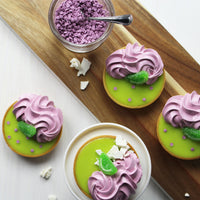 Lime curd sweet tarts topped with elderberry flavored meringue and purple sugar confetti decoration