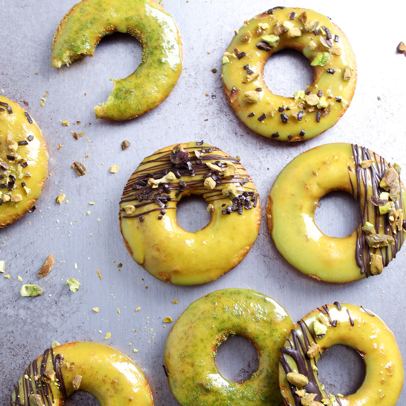 Vanilla Donuts with Pistachio flavored donut glaze and drizzled with dark chocolate and pistachio pieces
